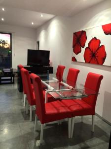 科尔多瓦图里斯提科卡里法尔公寓的一间用餐室,配有红色椅子、玻璃桌和钢琴