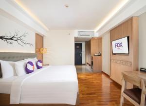 金巴兰FOX Hotel Jimbaran Beach的卧室配有一张白色大床和一张书桌