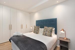 开普敦The Cosmo Luxury Suites by Totalstay的一间卧室配有一张大床和蓝色床头板