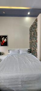 邦美蜀SKY HOMESTAY的卧室内的一张白色大床,带有石墙