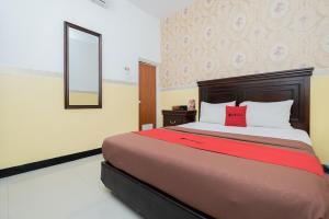 玛琅RedDoorz near Taman Krida Budaya Malang的一间卧室配有一张带红色枕头的大床