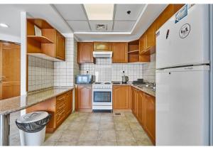迪拜Amazing 3BR Apartment next to Emirates Towers Metro in DIFC的厨房配有木制橱柜和白色冰箱。