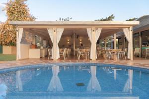 赫索尼索斯海星村酒店的一个带凉亭和桌椅的游泳池