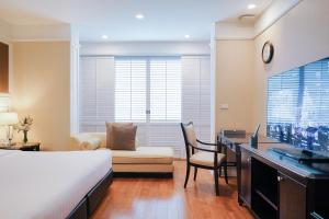 曼谷曼谷拉查丹利中心酒店的一间卧室配有一张床、一张书桌和一台电视。