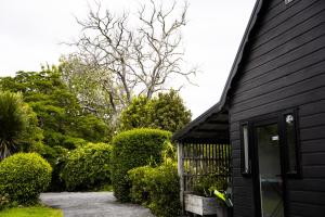 HaruruForest Waters Bungalow的黑色的房子,有门和灌木丛