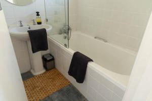 开普敦Studio Blue in Mouille Point的浴室配有白色浴缸、盥洗盆和浴缸。