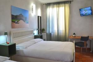 卡塞勒托瑞尼斯DOMUS Hotel的一间卧室配有两张床、一张桌子和一张书桌