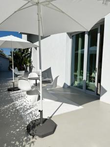 利多迪费尔莫CinziaHome Boutique B&B的庭院配有桌子、遮阳伞和椅子
