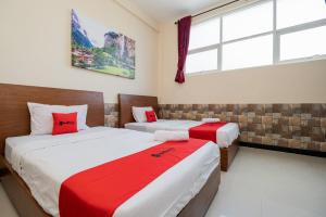 玛琅RedDoorz Syariah near Batu Night Spectacular的一间卧室配有两张红色和白色床单