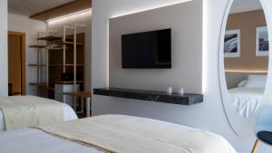 El ProvencioHOSPEDERIA BODEGA NUESTRA SEÑORA DEL ROSARIO的酒店客房设有两张床和一台墙上的电视。