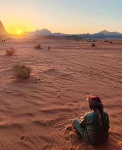瓦迪拉姆Shahrazad desert, Wadi Rum的坐在沙漠中观看日落的女人