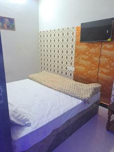 PratāpgarhHotel Divine and Restaurant的一间小卧室,配有一张床铺和墙上的电视