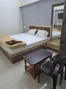 PratāpgarhHotel Divine and Restaurant的一间卧室配有一张床、一把椅子和一张桌子