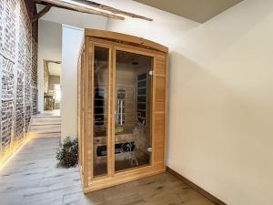 艾瓦耶Au Chat’Moineau的客房设有带玻璃门的大型木制橱柜。