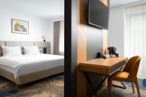 锡纳亚Alexandrion Experience的一间卧室配有一张床和一张书桌及电话