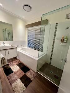 黄金海岸Private Gem in Pacific Pines的带浴缸和玻璃淋浴间的浴室。