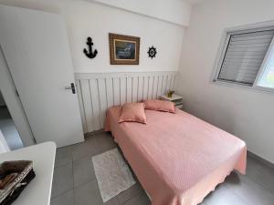 乌巴图巴Apt Familiar-Condomínio fechado UBATUBA的一间卧室配有粉红色的床和粉色毯子