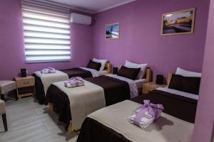 沙巴茨Smestaj & Spa Protić的一间设有三张床和紫色墙壁的房间
