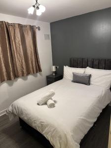 伍尔弗汉普顿Remarkable 2-Bed Apartment in Wolverhampton的卧室配有白色的床和帽子