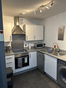 伍尔弗汉普顿Remarkable 2-Bed Apartment in Wolverhampton的厨房配有白色橱柜和炉灶烤箱。