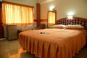 哥印拜陀Hotel City Tower的一间卧室配有一张带橙色床罩的大床