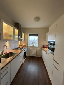 吕伐登Apartment with city skyline的厨房配有白色橱柜、水槽和窗户。