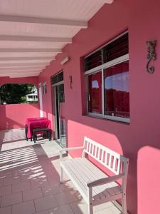 黑角Terrasse des Manguiers : logement indépendant的门廊上带长凳的粉红色房子