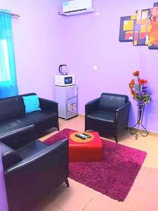杜阿拉Residence Sighaka - Studio Meublé VIP avec WiFi, Gardien, Parking的客厅配有黑色沙发和两把椅子