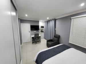 德班Vusi's Guesthouse的一间卧室配有一张床、一把椅子和一张书桌