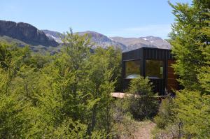 厄尔查尔坦Cerro Electrico - Off The Grid Tiny Houses的山丘上的黑色房子,背景是群山