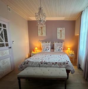 Chambre d'hôtes - La Pinstrie的一间卧室配有一张床和一个吊灯