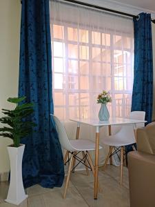 内罗毕Lux Suites Neema Court Furnished Apartments的一间带桌子和窗户的用餐室