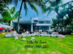 Xuyên MộcBiệt thự 5PN Resort Sanctuary HỒ Tràm ll Bãi biển riêng ll hồ bơi BBQ的一群坐在建筑物前面的草上的妇女