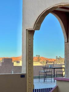 梅尔祖卡骆驼之家住宿加早餐旅馆的阳台的拱门,配有桌椅