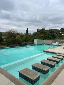 比勒陀利亚REGENCY APARTMENT HOTEL-ST@Y的一座蓝色海水和椅子的大型游泳池