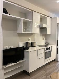 比勒陀利亚REGENCY APARTMENT HOTEL-ST@Y的厨房配有白色橱柜和平面电视。
