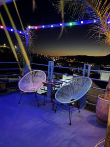 舍夫沙万USHA Guest House的阳台上的三把椅子和一张桌子在晚上