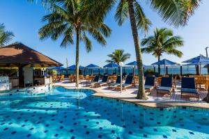 邦比尼亚斯Hotel Vila do Farol的一个带椅子和棕榈树的游泳池以及大海
