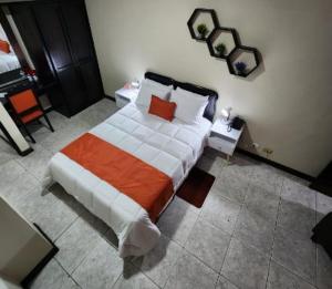 埃雷迪亚Hotel América Heredia的一间卧室配有一张带橙色和白色毯子的床