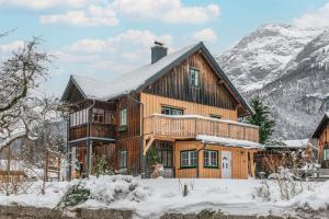格伦德尔湖Ferienwohnung Haus Sonnenschein的一座大木屋,位于雪中,与群山交织