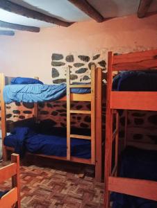 奥兰太坦波Sacred Point的一间石墙客房的卧室,配有三张双层床