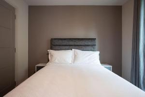 贝尔法斯特Brand New, Luxury & with Terrace的卧室内的一张带白色床单和枕头的床