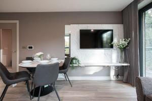 贝尔法斯特Brand New, Luxury & with Terrace的一间设有桌子和墙上电视的用餐室