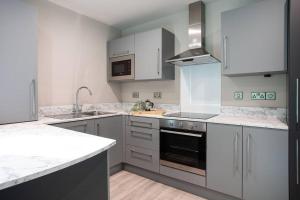 贝尔法斯特Brand New, Luxury & with Terrace的厨房配有白色橱柜和炉灶烤箱。