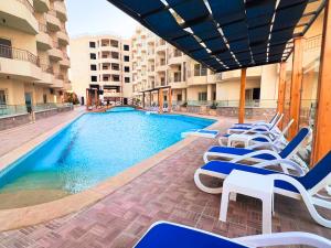 伊斯梅利亚Beach Front Apartment in Hurghada La Quinta Beach Compound的一座带躺椅的游泳池位于大楼旁