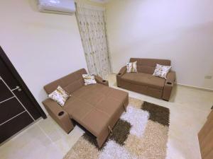 伊斯梅利亚Beach Front Apartment in Hurghada La Quinta Beach Compound的客厅配有2张棕色沙发和地毯