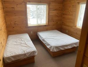 BrimleyBrimley Lodge / Sleeps 36 / Snowmobile & ORV Trail的小木屋内的两张床,设有两扇窗户