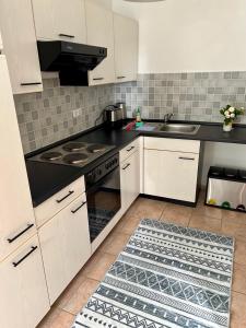 PlathNussbaumhof mit Koppel的厨房配有白色橱柜和黑色台面