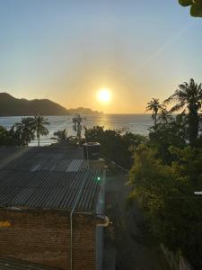 塔甘加Sunset View, Taganga的落在海洋上的日落,有一座建筑和棕榈树