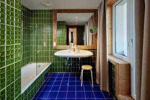 米特西尔科格勒运动酒店的绿色瓷砖浴室设有水槽和浴缸